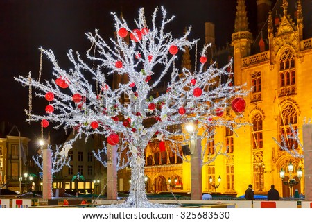 Decorated and illuminated Christmas tree on the rink in front of Province Court at Market Place in the center of Bruges at night, Belgium