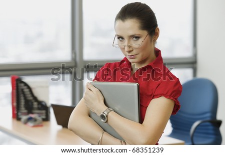 Woman with the red shirt in the office with a laptop
