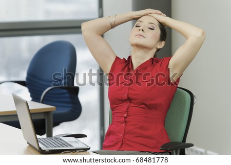 Woman with the red shirt in the office with a laptop while resting