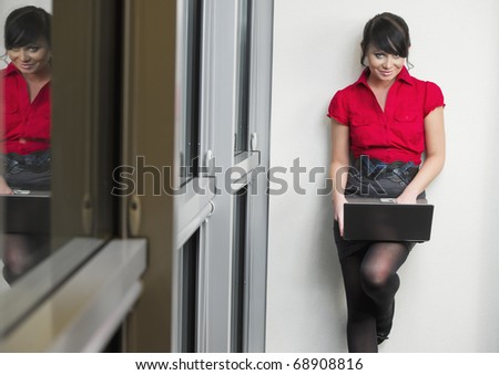 Woman with the red dress in the office with a laptop