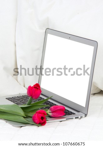 Modern popular laptop with tulips flowers and white screen isolated on a white background
