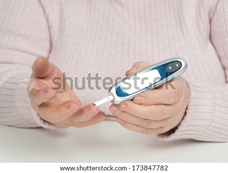 Diabetes patient senior woman measuring glucose level blood test with glucometer and small drop of blood