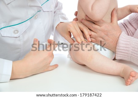 Doctors hand with syringe vaccinating child baby flu injection shot in leg isolated on a white background