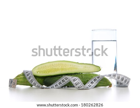 Dietting breakfast diabetes weight loss concept with tape measure organic green cucumbers and glass of drinking water on a white background