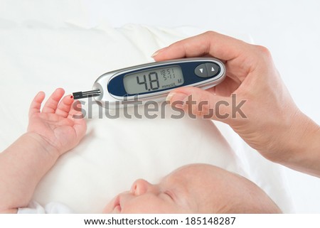 Doctor hand measuring glucose level blood test from diabetes patient child baby using glucometer and small drop of blood from finger and test strips isolated on a white background