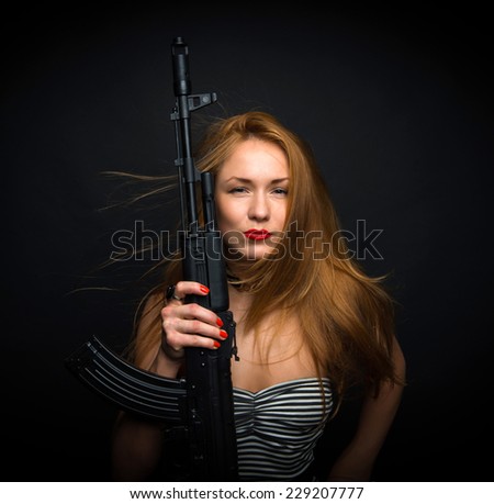 Portrait of sexy fashion glamour woman holding up her weapon assault rifle gun on a black background