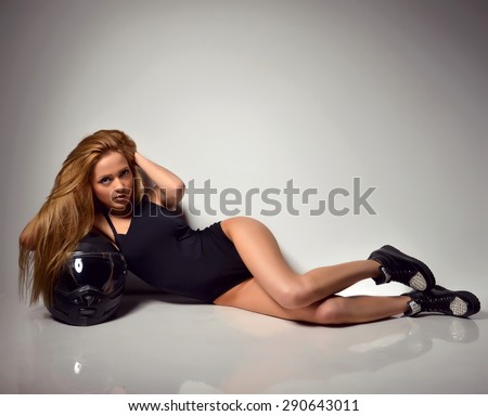 Sexy young beautiful full body blonde russian woman lying on the floor with black motorcycle helmet