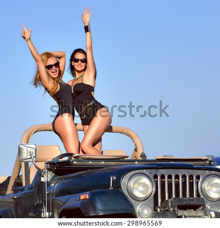 Happy beautiful young girls sitting in beach truck car in sunglasses on sunny summer day