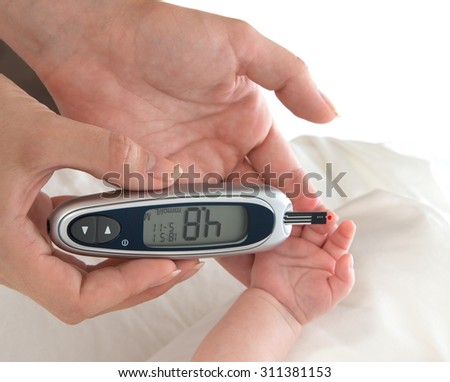 Doctor hand measuring glucose level blood chemistry test from diabetes patient child baby using glucometer and small drop of blood from finger and test strips isolated on a white background