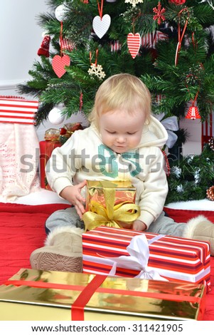 New year concept. Child baby toddler kid sitting under decorated christmas tree preparing presents gifts for celebration isolated on a white background
