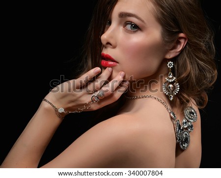 Portrait of young brunette woman with vintage silver diamond pendant jewelry and earrings on black background