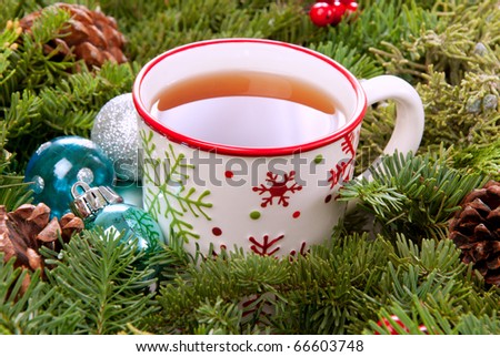 Christmas mug with tea decorated  with red and green snowflakes pine and fir cone ornament in the morning