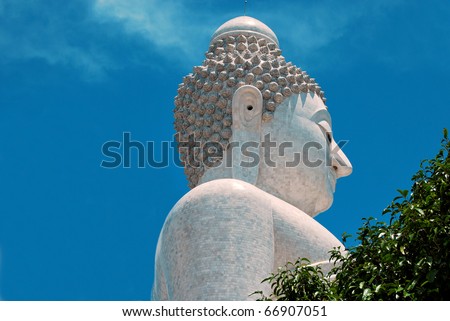 The Biggest  white holy Buddha head  in the world on Phuket Mountain Thailand surrounded by green tropical trees isolated on a blue sky background
