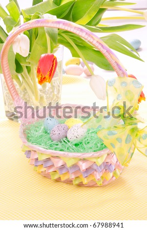 Easter Painted Colorful eggs in pink basket for Christian sunday morning decorated with spring tulips on a pastel color background