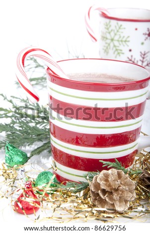 Two Christmas cups with Hot cocoa, candy canes, decorated with candies, cones and isolated on a white background