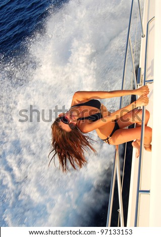 Pretty young slim sexy brunette woman in sunglasses sailboat yacht in black stylish bikini on private speed-boat on vacation in summer time happy sailing in Mediterranean sea