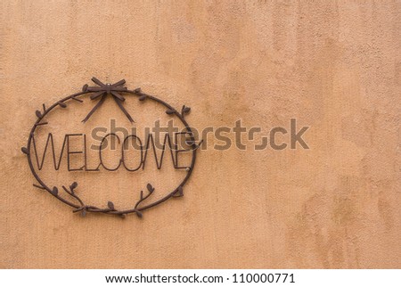 steel cast welcome sign on earth tone rough textured cement wall