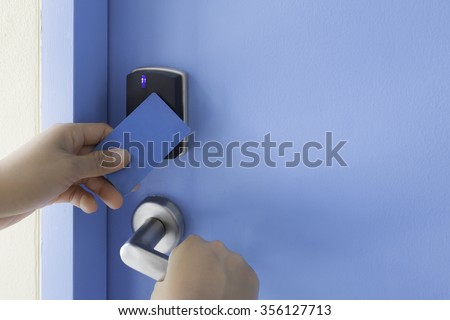 left hand hold key card touch on black electronic pad lock access control with right hand turn stainless steel door handle on blue door