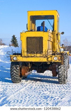 The powerful yellow bulldozer cleaning heavy snow