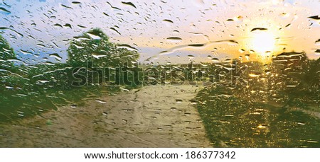Sun shower. Drops of rain on windscreen against sunset
