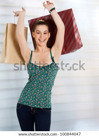 Happy woman at a shopping center holding bags with arms open