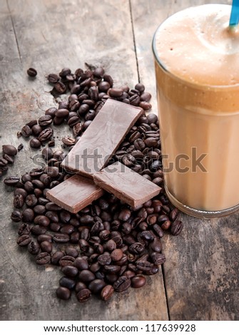 raw coffee beans and chocolate on old wooden plank