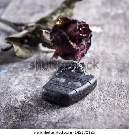 dried rose and car keys on the table, close up photo