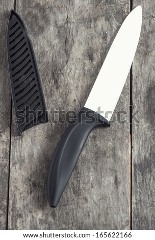 ceramic knife on old wooden plank, close up