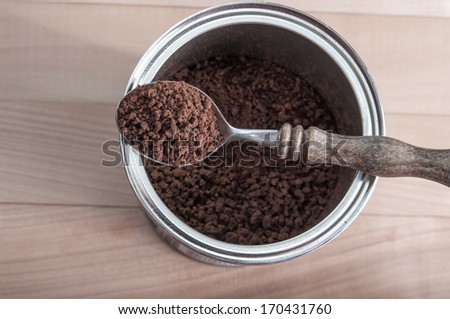 Open package of instant coffee and spoon over wooden background