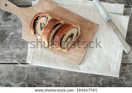 poppy seed Roll on a wooden surface, closeup
