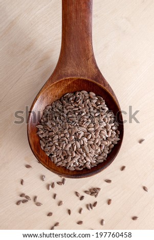 flax seed in wooden spoon over wooden backgroun, from above