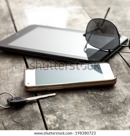 mobile phone, tablet and sunglasses on table, backlit