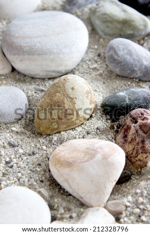 Sea stones collection on sand background, natural light