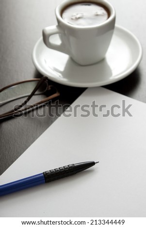 coffee, white paper and pen on a black table