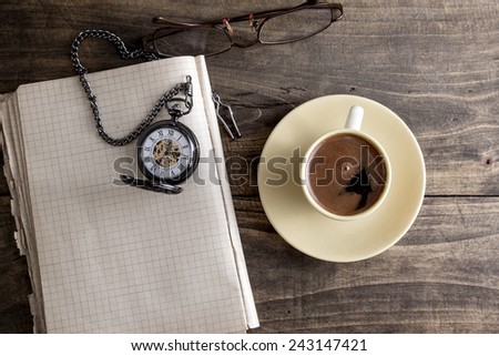Vintage pocket watch with cup of coffee on old book from above
