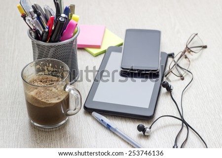 Digital tablet computer with sticky note paper and cup of coffee on wooden desk