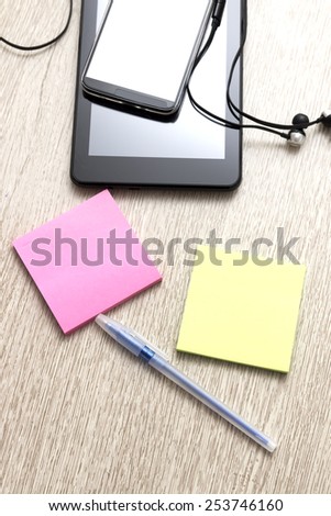 Digital tablet computer and phone  with sticky note paper on  wooden desk.