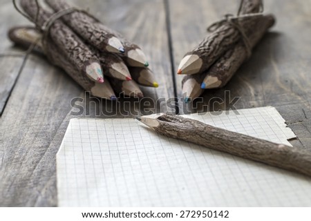 Group of bark covered branch multicolored pencils on wooden  background