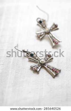 Jewelry cross earrings on old wooden surface, natural light