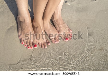 feet of child and mom in the sea sand, from above