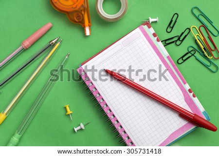 School materials such as crayons, notebooks, clips, stapler, prencils over green background