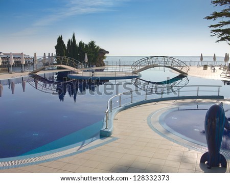 swimming pool with tree, bridges and white umbrella