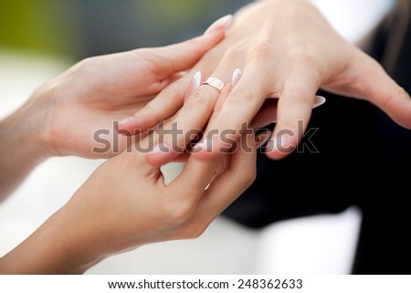 Bride wears a ring on groom\'s finger