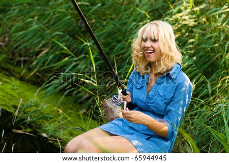 a woman fishes in the river fishing-rod. on a background a river reed