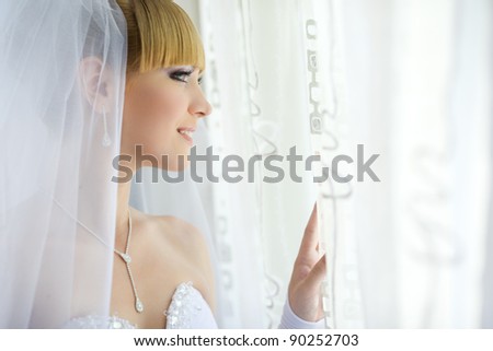 charming young bride looking out the window and smiling