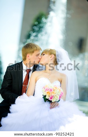 Bride and groom kissing by the fountain