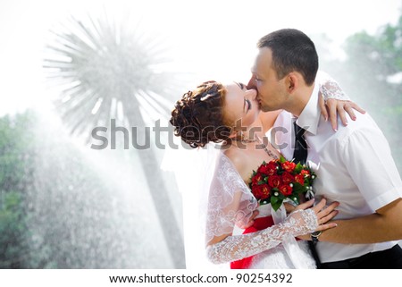 Bride and groom kissing near a fountain