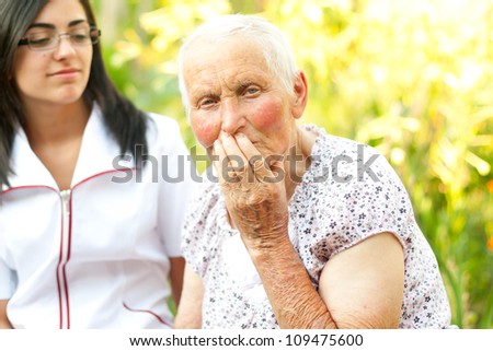 Sad elderly woman with her hand on her mouth.