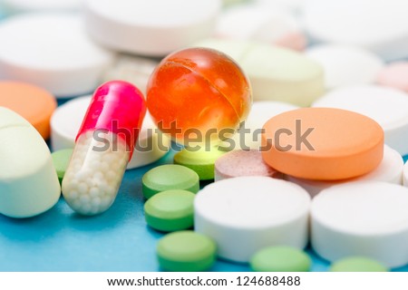 Various drugs, nutrient supplements and vitamins on blue background.