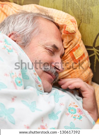Peaceful senior man sleeping in bed smiling.